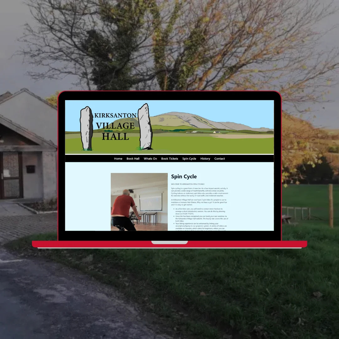 Laptop showing the Kirksanton Village Hall website spin cycle page with a person cycling on a stationary bike, set against a rural Cumbrian countryside backdrop