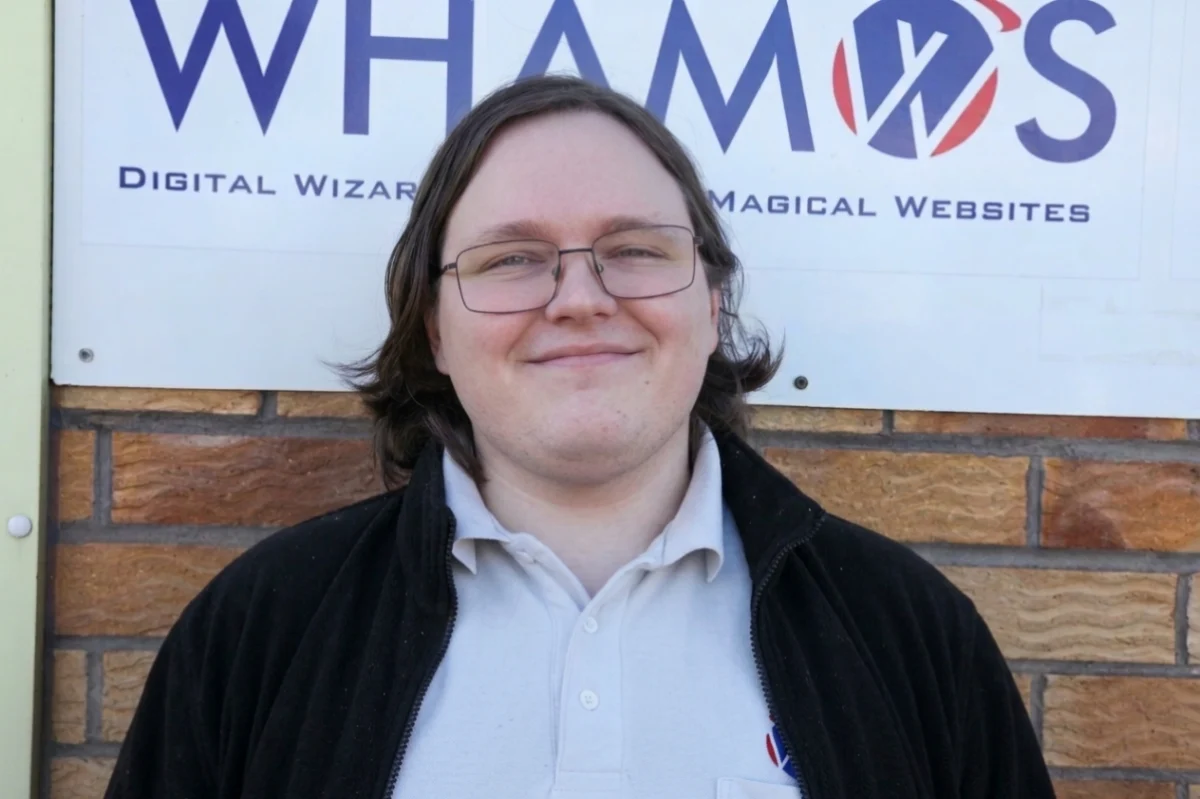 Matthew smiling in front of Whamos sign