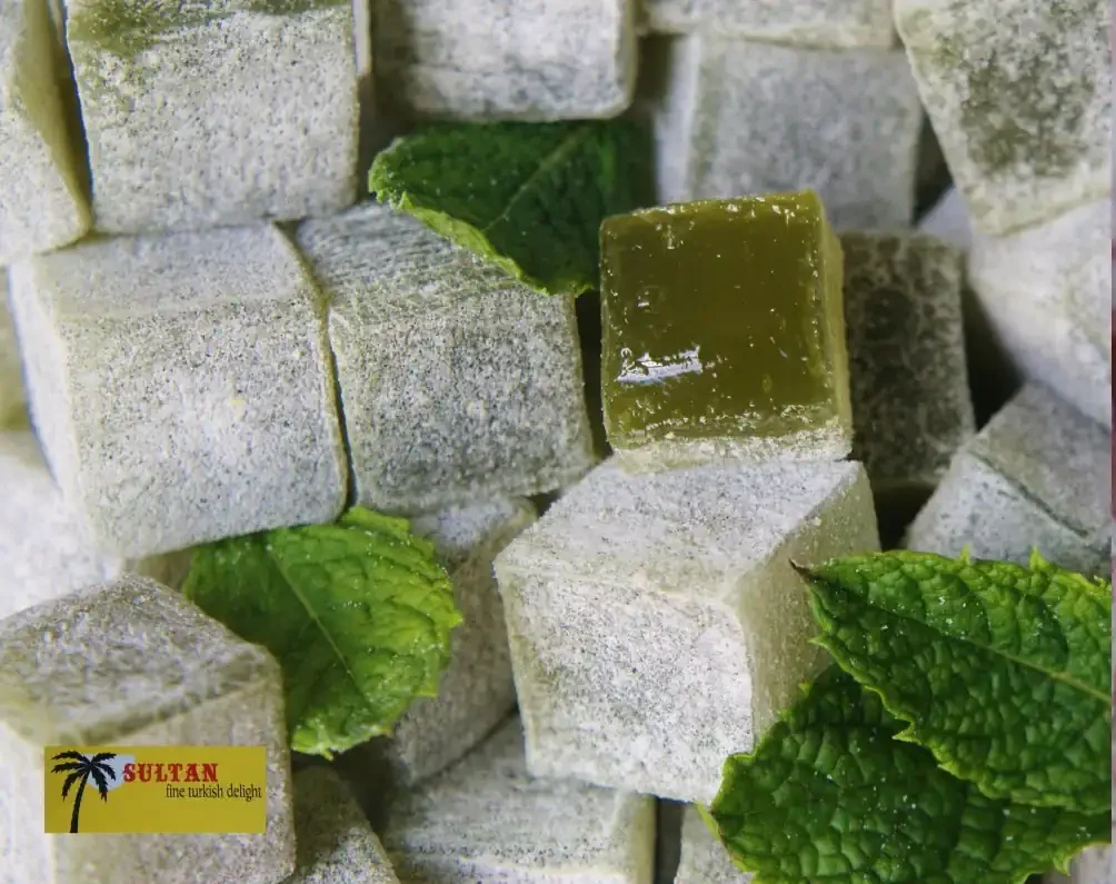 Close-up of Sultan Delights mint Turkish delight pieces dusted with icing sugar and fresh mint leaves