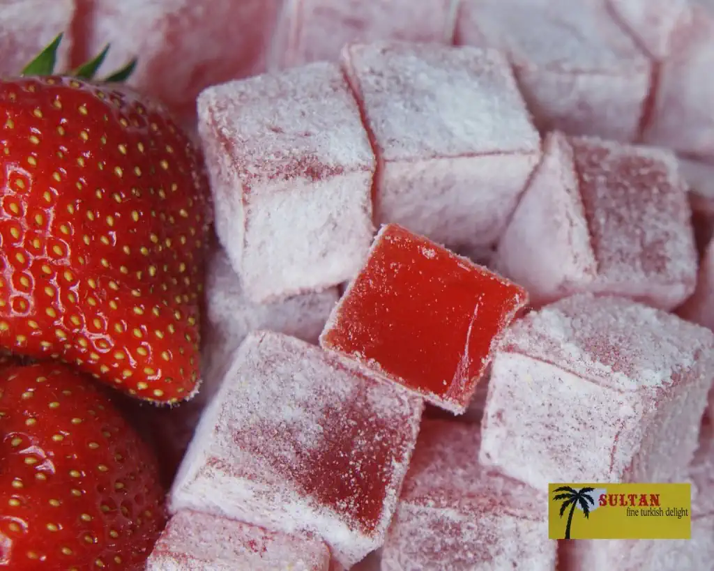 Close-up of Sultan Delights strawberry Turkish delight pieces with fresh strawberries